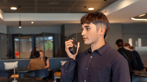 Team member using a Tait handheld radio for instant workplace communications in a small-to-medium-sized business environment.