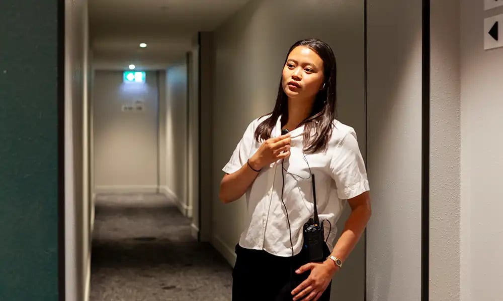 Staff member using a handheld two-way radio for team communications and coordination in a hospitality environment.