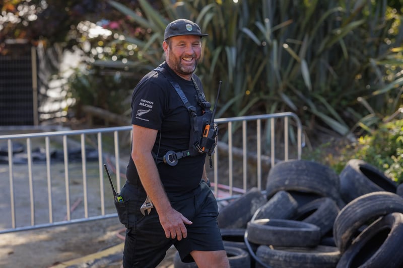 Event staff member wearing a radio harness walks beside the race course.