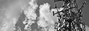 Communications tower with multiple radio antennas against a cloudy sky.